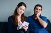 a man and a woman on a couch looking at the woman's notepad as she writes in it